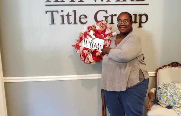 Smiling woman, Latanya Moultry, holding a wreath after closing on her new home.