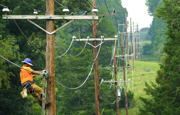 Worker installing fiber line on an existing electric pole.