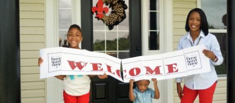 Photo of family standing in front of a home purchased with Rural Development funding.