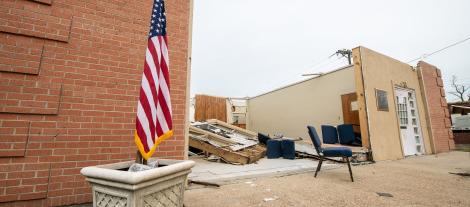 Image of American flag and building after disaster 