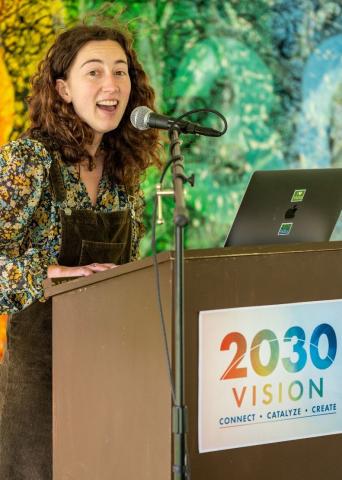 The Island Institute Fellow described in the story is pictured at a podium with a sign on the front reading "2030 Vision."