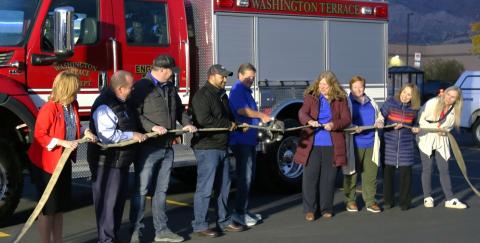 Key members of Washington Terrace, Utah community participating in a ribbon cutting ceremony using a firehose and "Jaws of Life Shears" instead of customary red ribbon and scissors.
