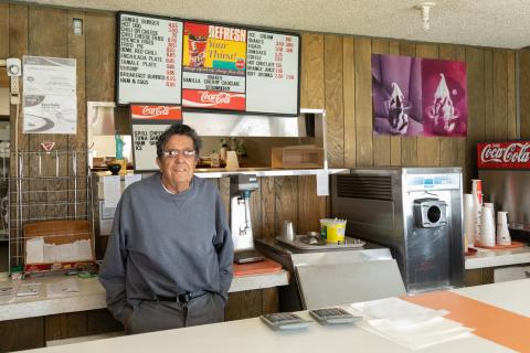 man standing behind a diner counter with menu behind hiim