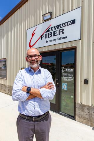 A man in a blue shirt stands outside a building owned by Emery Telcom in San Juan County, Utah.