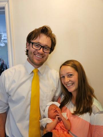 Cody and Melissa Olsen, a young adult Caucasian couple, smiling while Melissa holds their new baby girl.