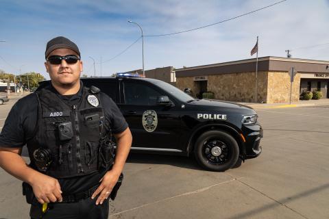 Police officer in front of cruiser on road in Wagner