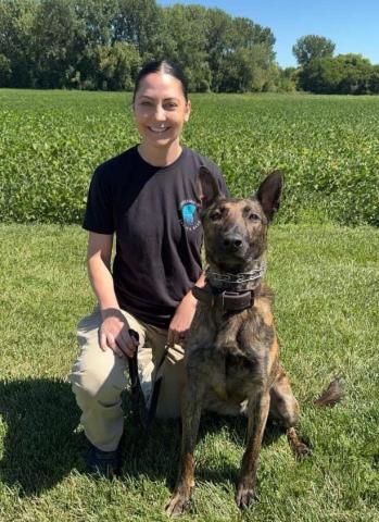 a female police officer with a police dog in a grassy area