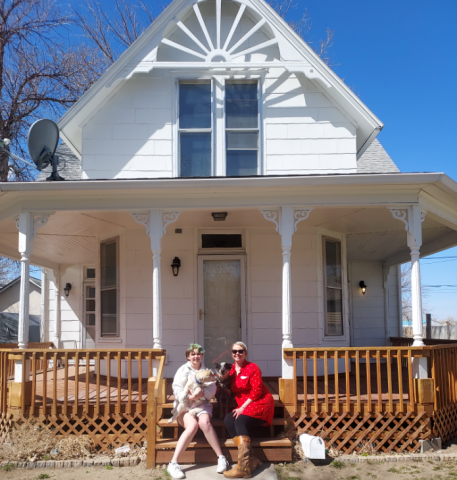 Hayley and her daughter sit on the front steps of their new home.