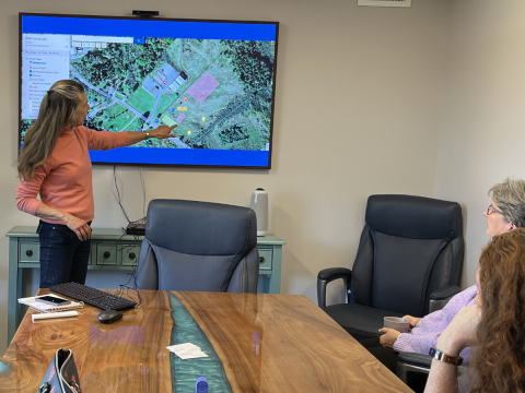A woman points to a map showing the layout of the Downeast Restorative Garden in a conference room.