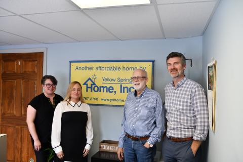 People standing in front of sign in office. 