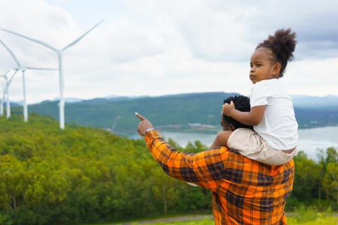 Image of a father and child looking at clean energy through wind turbines