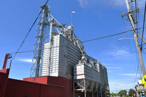 Large grain feed mill located at small town intersection. 