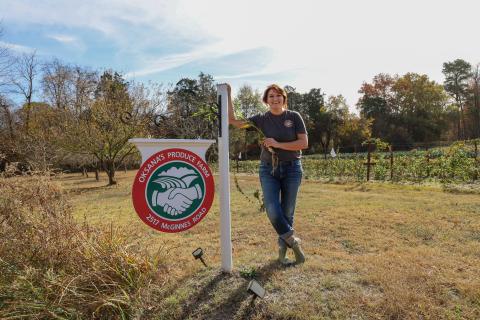 Oksana standing in front of her farm sign