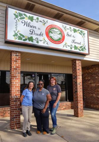 Oksana and two USDA Rural Development staff members in front of her new kitchen