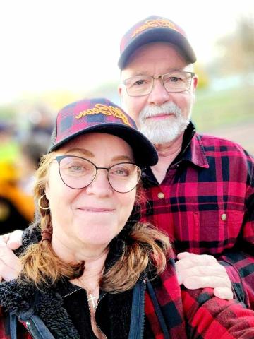 A man and woman pose for a portrait wearing baseball caps and outdoor apparel.