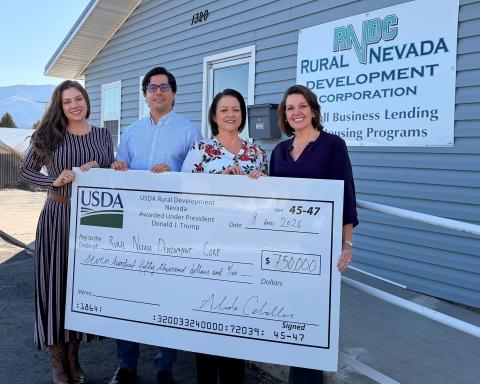 Four people pose with an oversized check representing USDA investment in rural business.