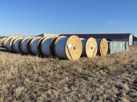 Large rolls of fiber optic cable in a field.