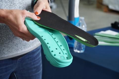 A person holds two foam insoles for shoes.