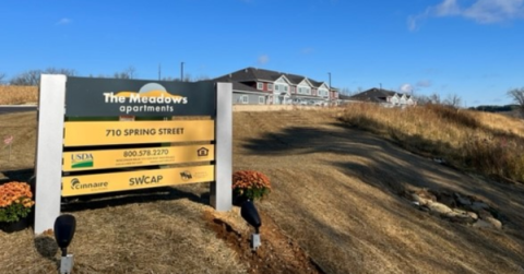 Sign with apartment building behind it