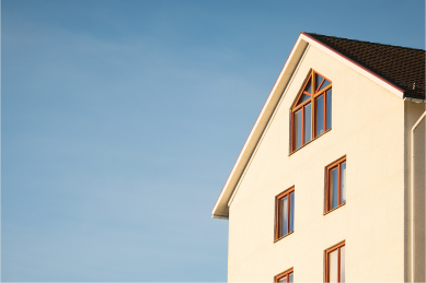 Image of three story apartment building with spanish tile roofing and stucco style siding. The windows appear to be facing the sun that is setting so the building has a warm glow to it.