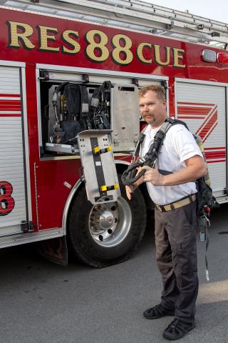 Assistant Chief William Stanley dons a SCBA pack that can be refilled on Rescue 88filled