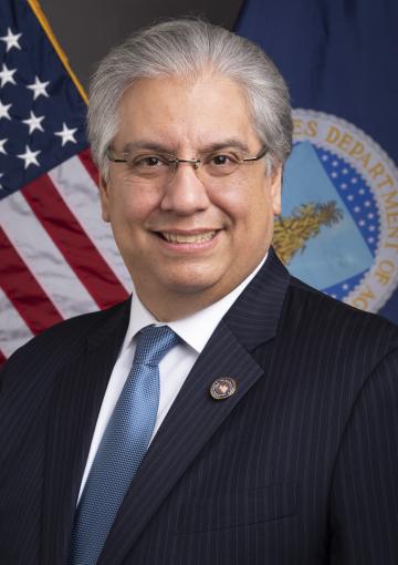 Smiling man standing in front of an American flag and the USDA flag; Maximiliano Trujillo, State Director for Puerto Rico 