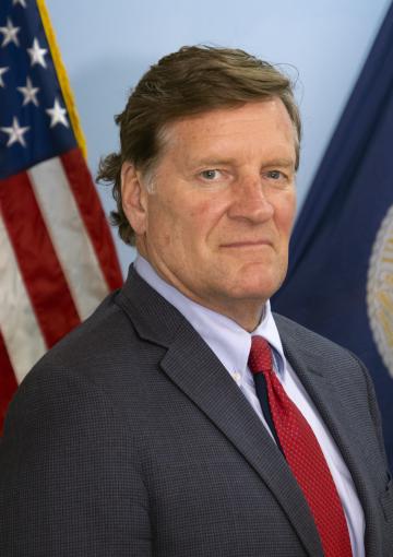 photo of USDA RD North Dakota State Director Thomas Campbell. Behind him are two flags, the US flag on the left and USDA flag on the right.