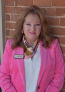 Joyce White in pink blazer, natural light, outdoors near a brick wall