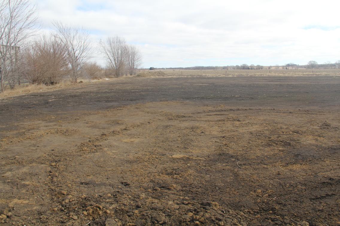 A field has been prepared for development, with a tree line and grass in the background.