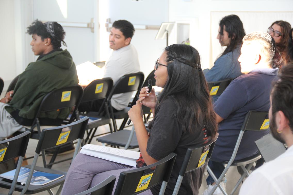 group of people sitting in chairs looking forward to something outside of frame