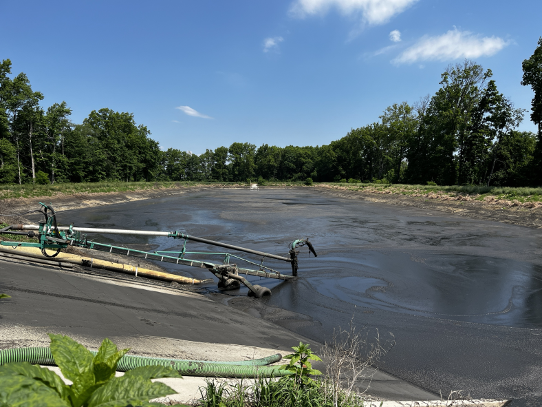 Bio-fertilizer storage lagoon surrounded by trees.