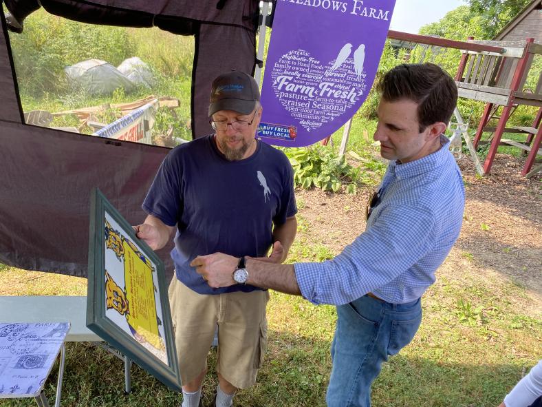 Greg Boulos, owner of Blackberry Meadows Farm in Natrona Heights, about 25 miles northeast of Pittsburgh, shows one of his menus off to Rep. Chris Deluzio