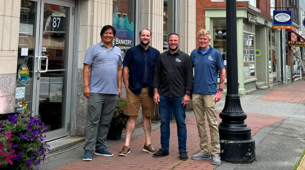 Brian Eng of Sustaine and the three owners of The Bankery and Skowhegan Fleuriste stand on the sidewalk in front of The Bankery with other businesses visible in the background.