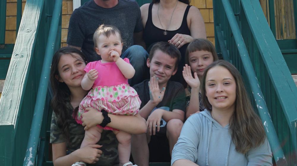 The LaRue Family sits on the steps of their new home