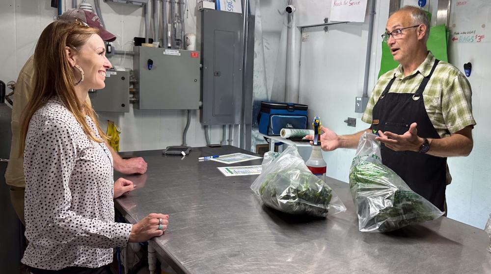 State Director Julia Hnilicka smiles at local business owner Henry Krull as he bags up lettuce and explains hydroponic farming.
