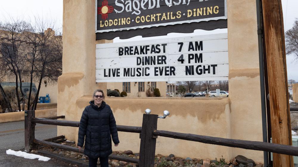 Woman standing in front of Sagebrush Inn sign