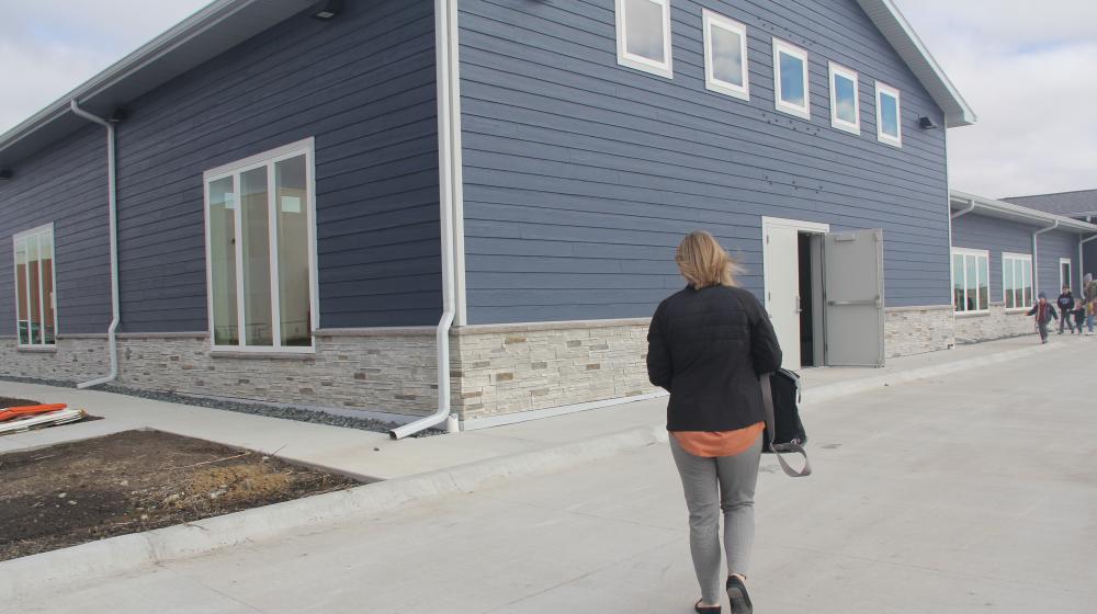 A woman with a bag walks towards the door of a newly built childcare center.