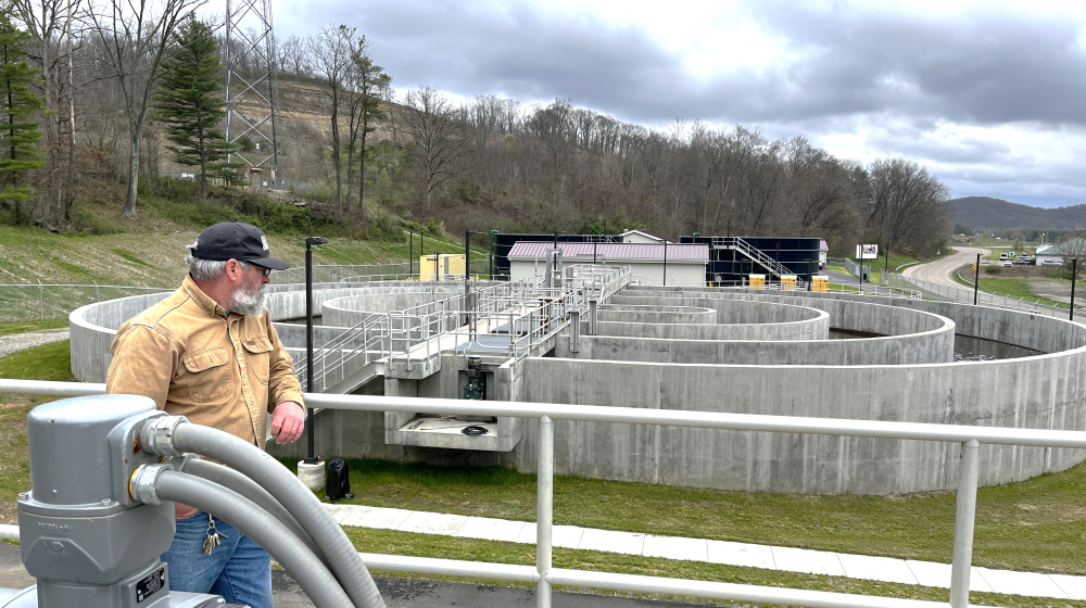 Man standing by wastewater plant in rural area. 