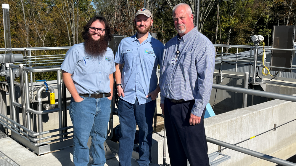 Men standing on top of wastewater plant building.