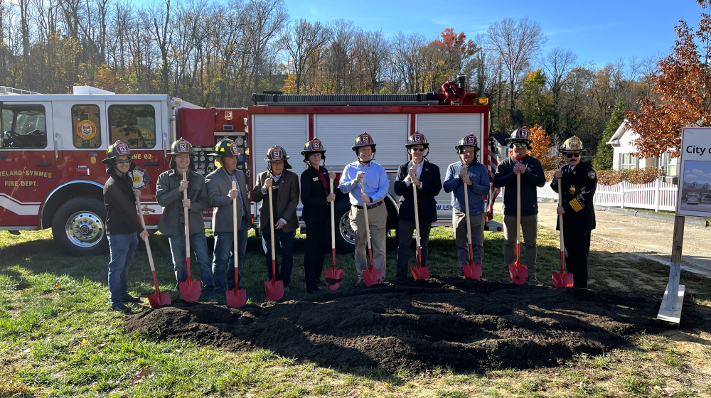 People standing in front of a fire truck in a field.