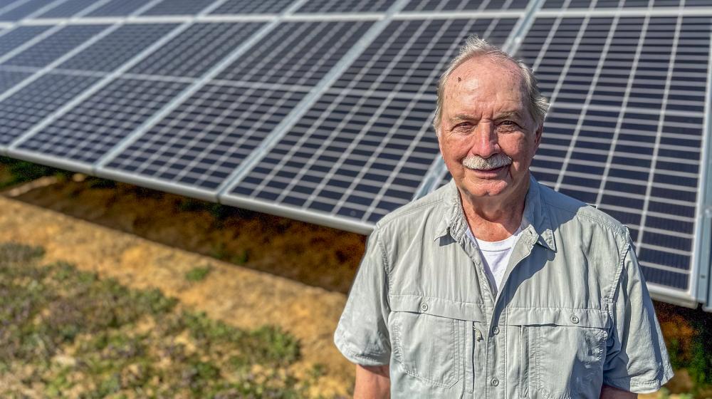 Bob Threewitts standing in front of his ground-mounted solar panels