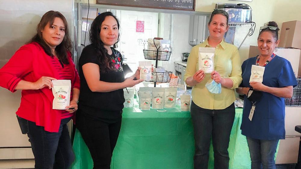 Staff from Back Yard Farms hold packages of apple chips that were just produced and ready for sale using the freeze-drying method.
