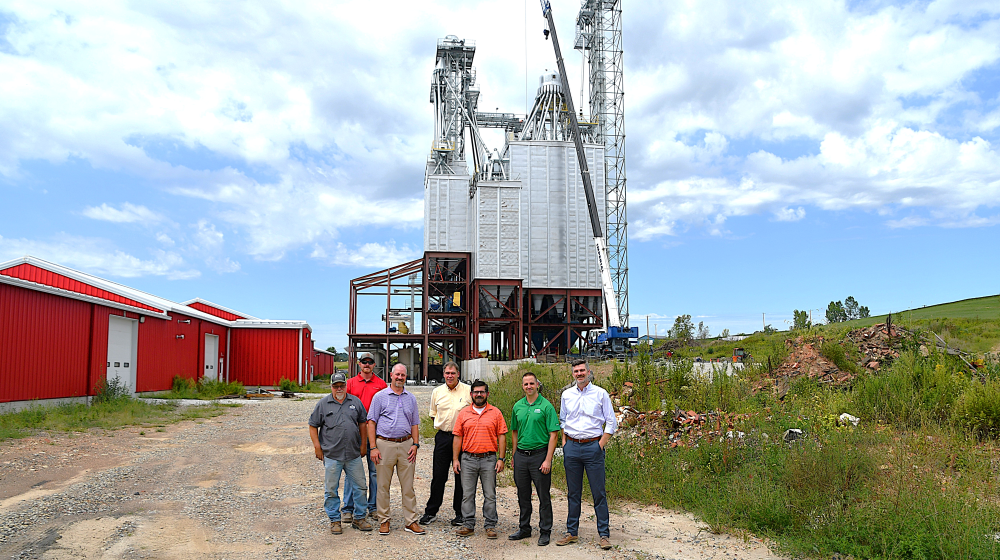 Group standing in front of feed mill under construction