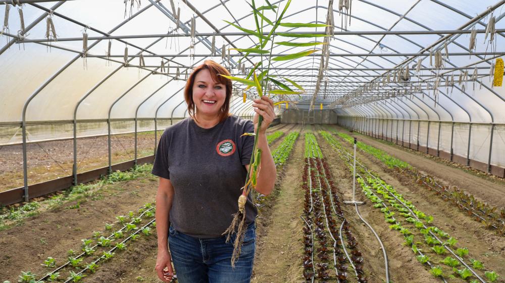 Oksana holding a piece of freshly picked ginger in her greenhouse