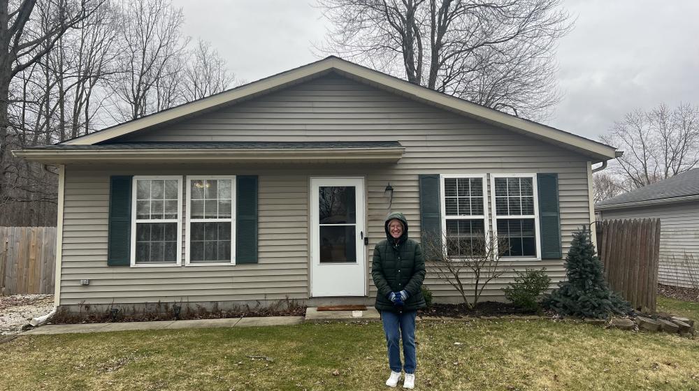 Homeowner stands out front of new home purchased with help from the USDA Single Family Housing Direct Loan program.