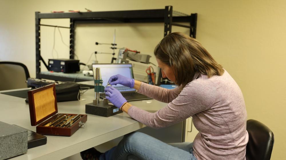 A woman bends over samples in a laboratory environment.