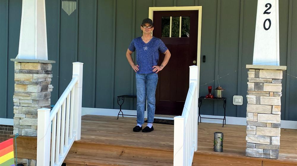 Smiling man standing on porch of his new house.