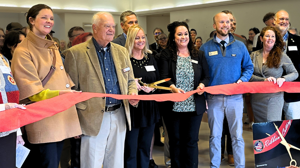 Smiling people hold a ribbon inside the Maine Arts Academy during the official ribbon-cutting ceremony.