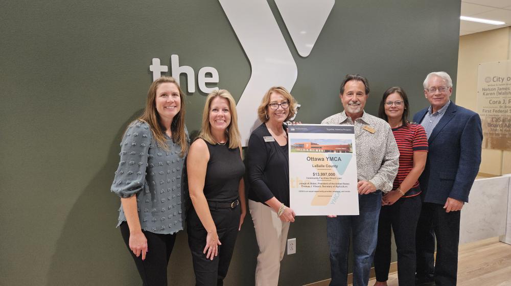 Picture of USDA Rural Development team presenting award poster to YMCA Leadership.