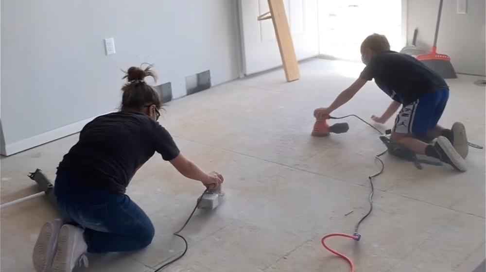 Male and female sanding a floor.